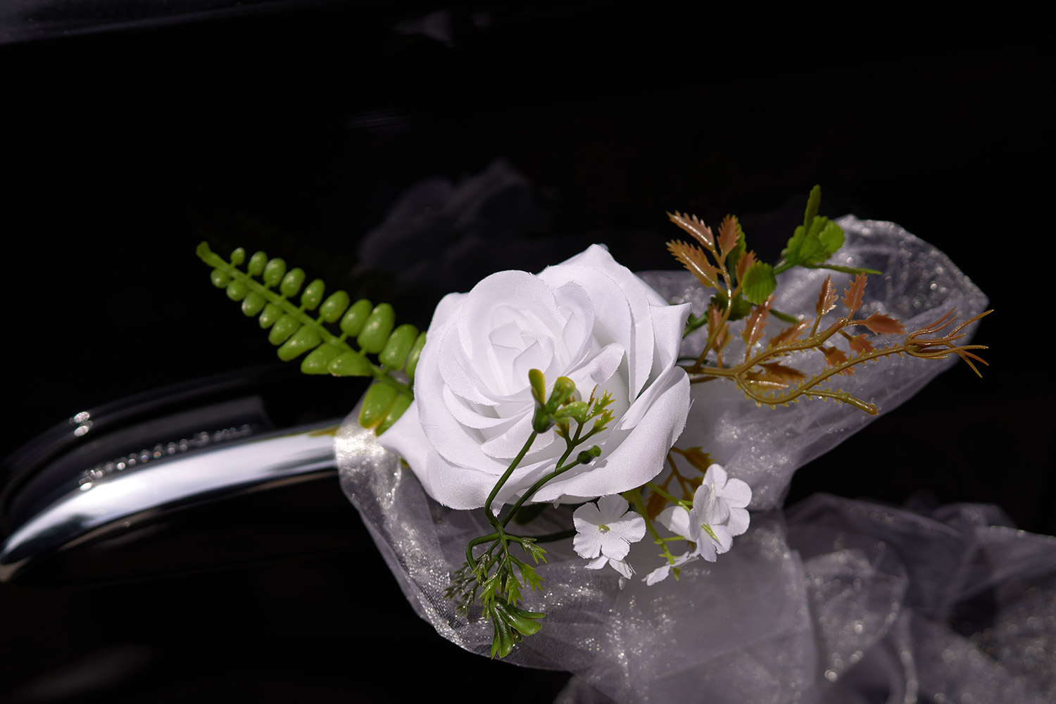 Dekoblumen für Hochzeitsauto mit Tüll. Nahaufnahme Kunstblume auf Autotür | Autovermietung Arndt