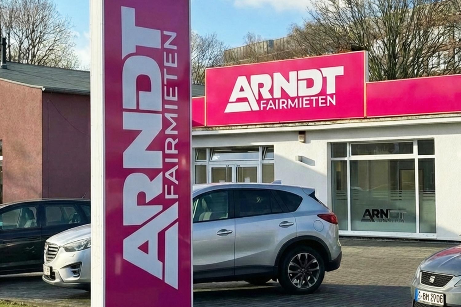 ARNDТ Fairmieten | Schild vor der Autovermietung Arndt Station Essen mit parkendem Mietwagen