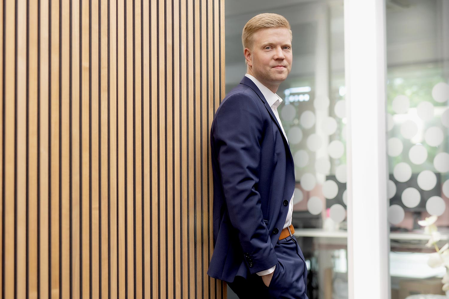 Moritz Arndt im Anzug steht lächelnd im Arndt Gebäude in Neuss | Autovermietung Arndt